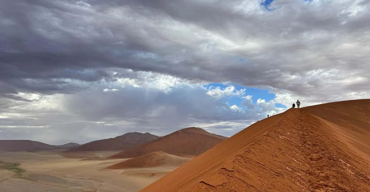 Travellers climbing a red dune at sunrise on a 2-day Sossusvlei tour in the Namib Desert, Namibia